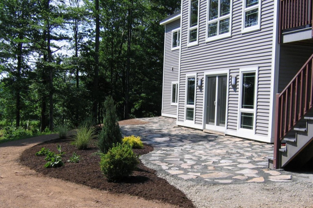 configuration filedstone patio in front of house and wooden stairs in forest and small garden